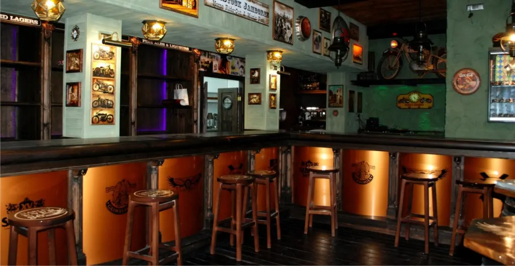 Interior de una taberna temática con barra iluminada y decoración antigua