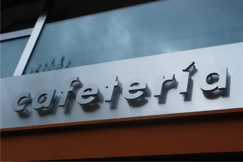 Letras corpóreas metalizadas «cafetería» en una fachada