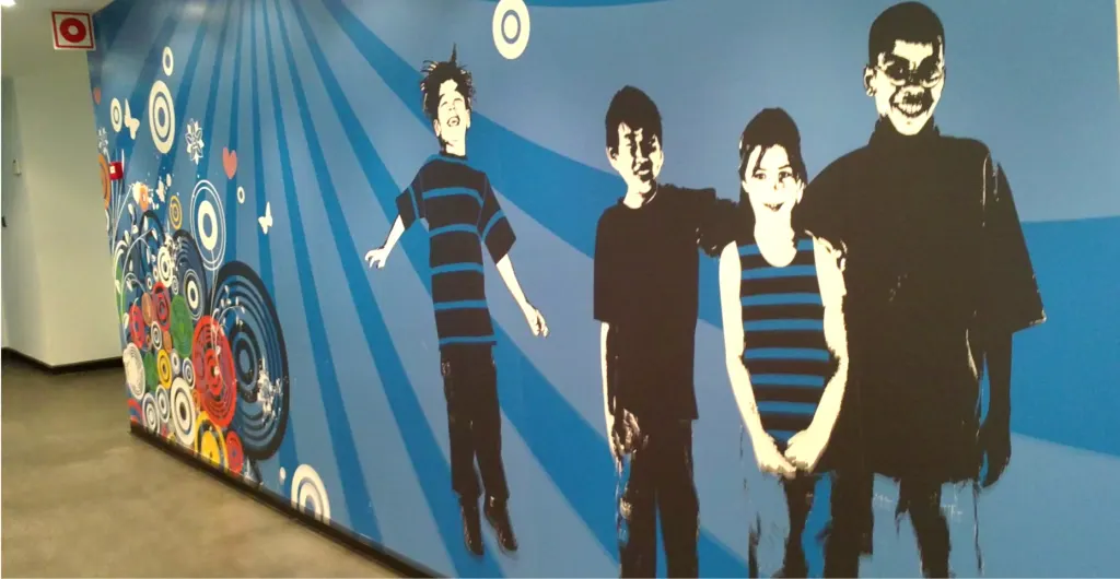 Mural impreso con siluetas de jóvenes y motivos gráficos en un pasillo