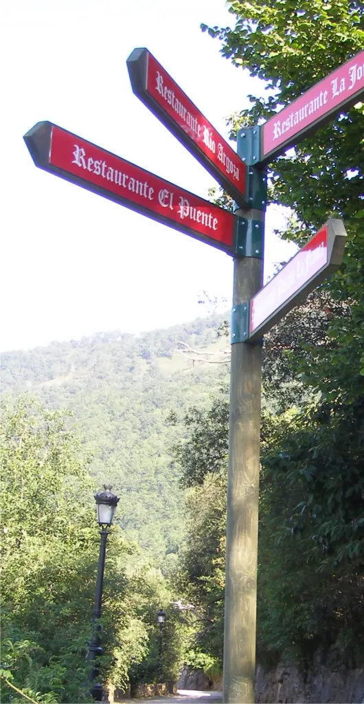 Poste de señalización direccional con flechas en un entorno rural