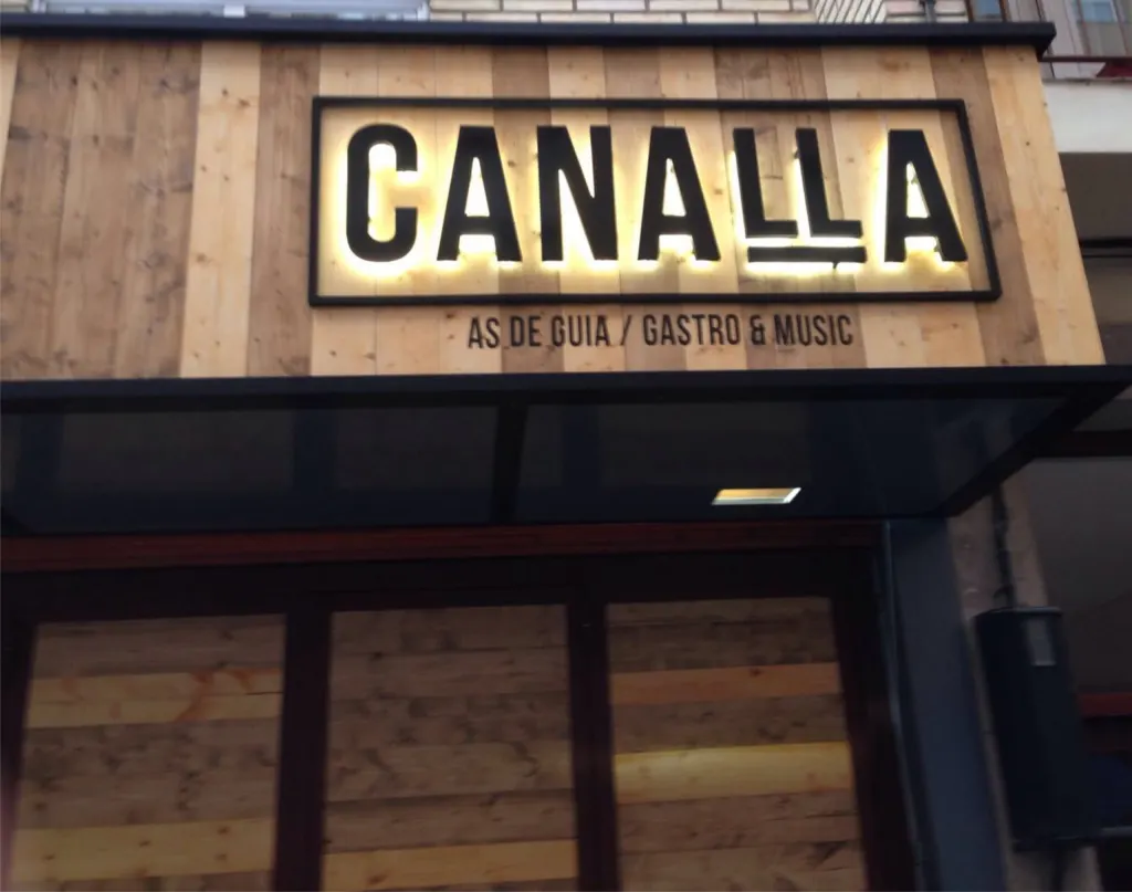 Rótulo luminoso «Canalla» sobre una fachada revestida de madera