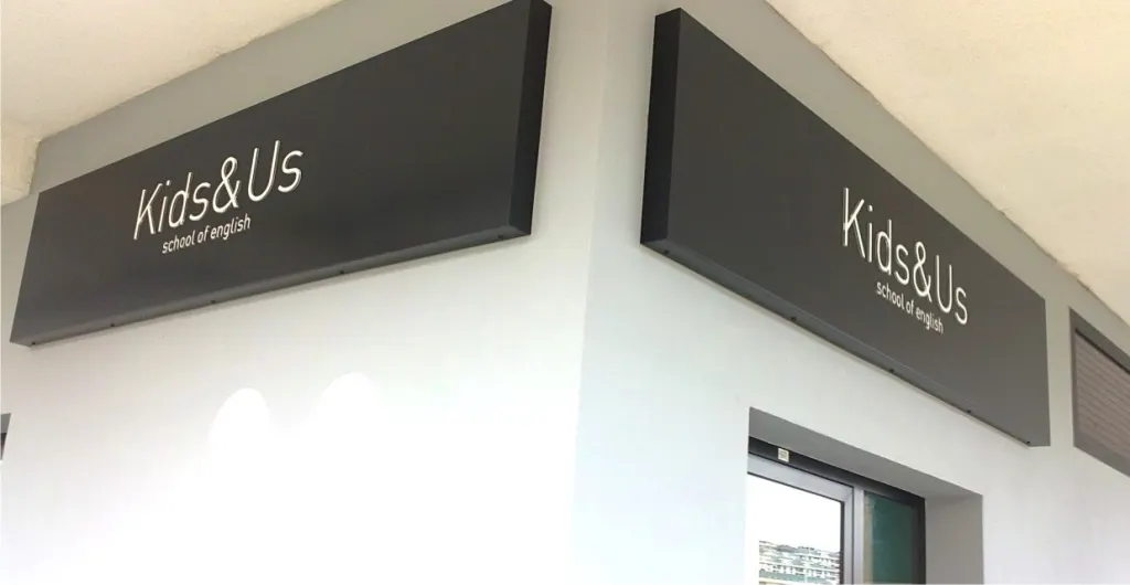 Rótulos en caja de Kids&Us en la fachada de una academia