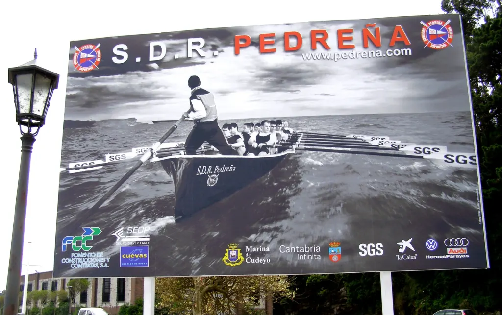 Valla publicitaria de la S.D.R. Pedreña con una fotografía de remo